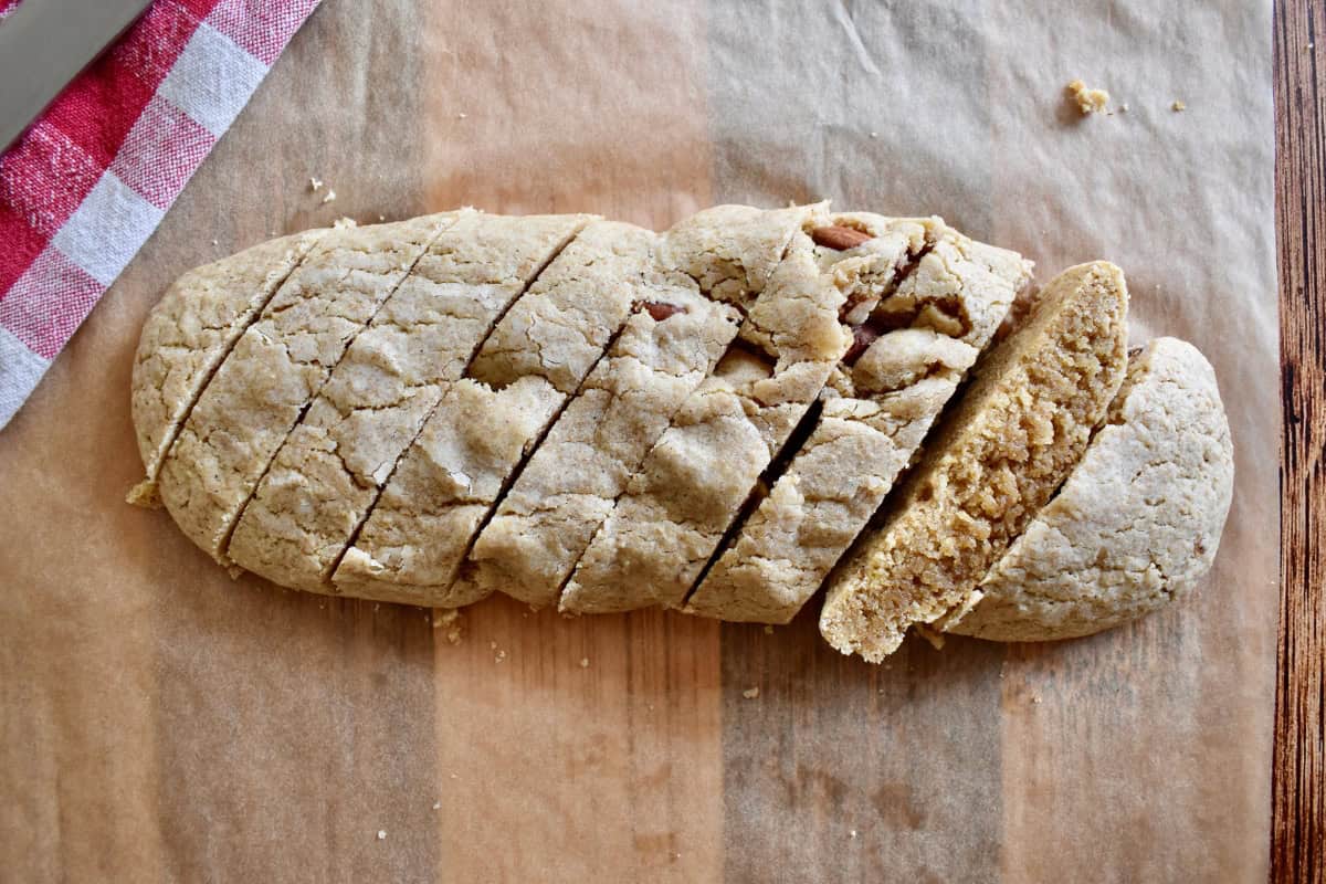 Log dough cut into strips on a cutting board. 