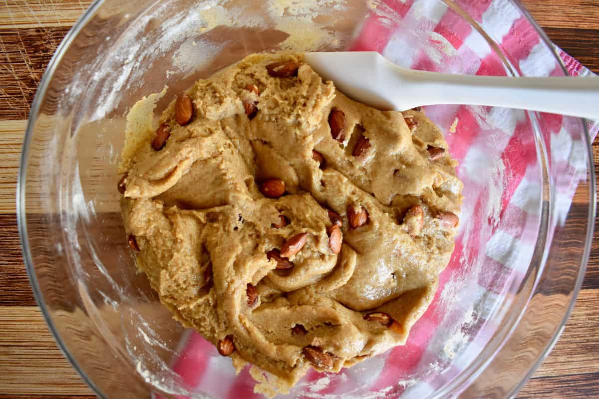 Dough for the cantucci in a glass bowl with almonds mixed in. 