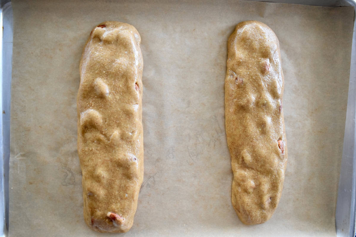 Cantucci dough shaped into logs on a lined baking sheet. 