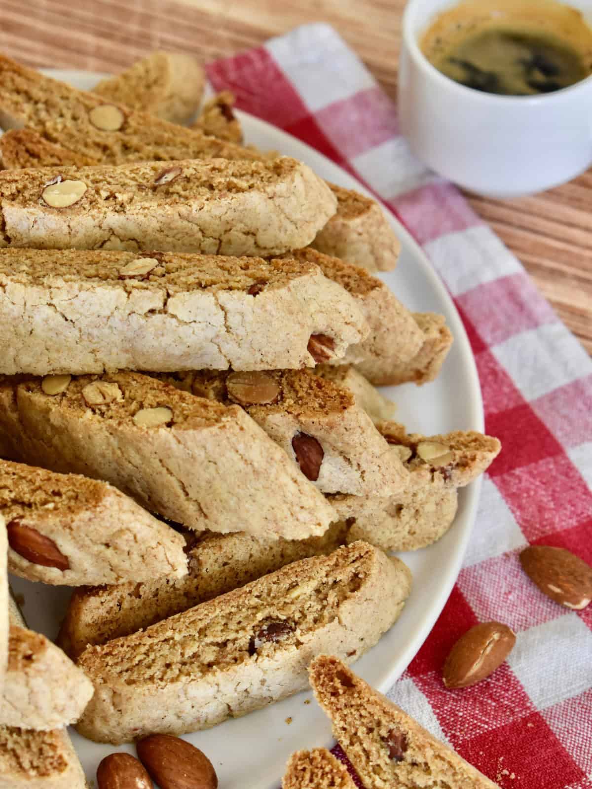 Whole Wheat Biscotti on a white plate with a checkered napkin and cup of coffee. 