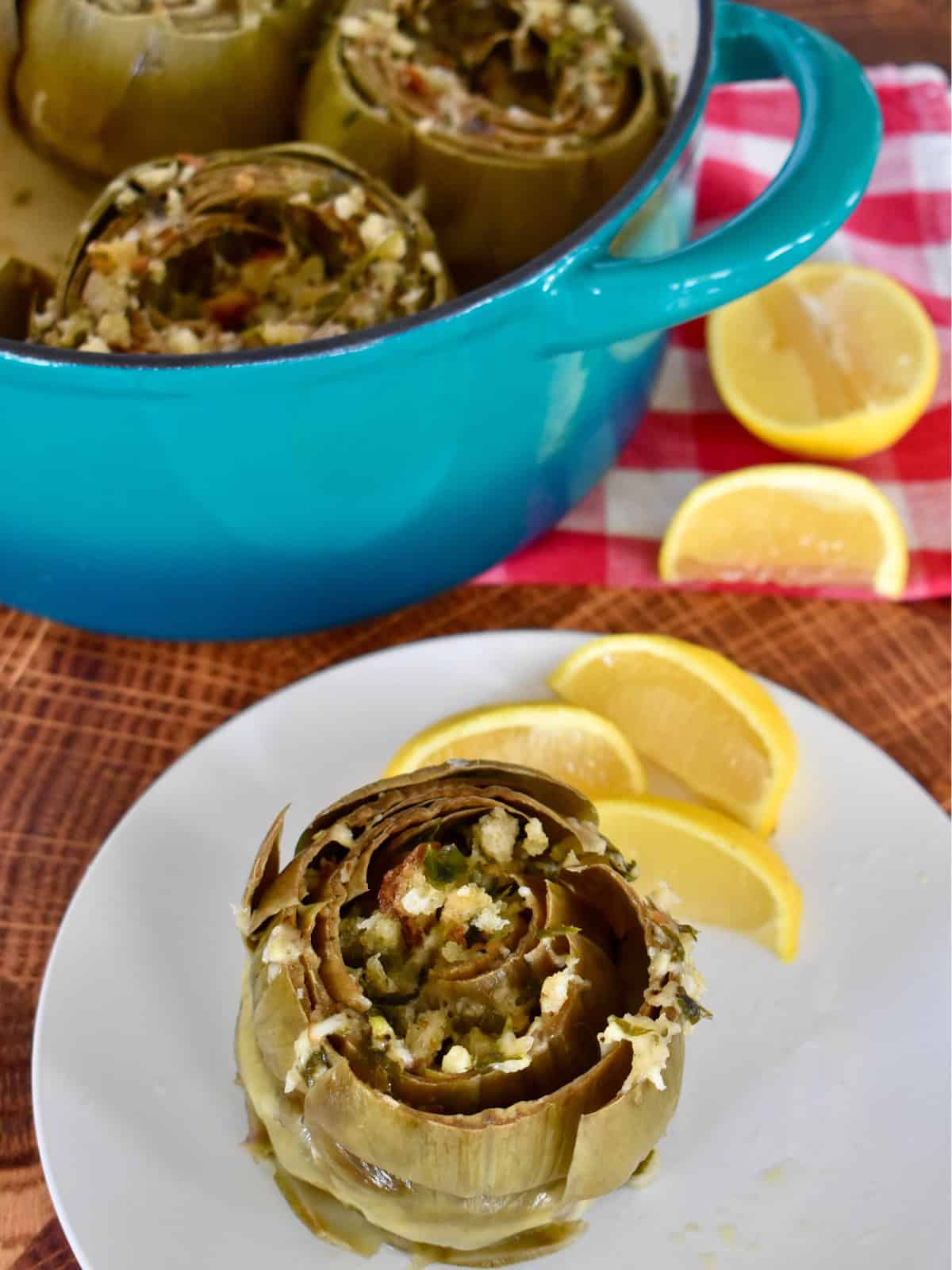 Italian Stuffed Artichoke on a white plate with a lemon wedge. 