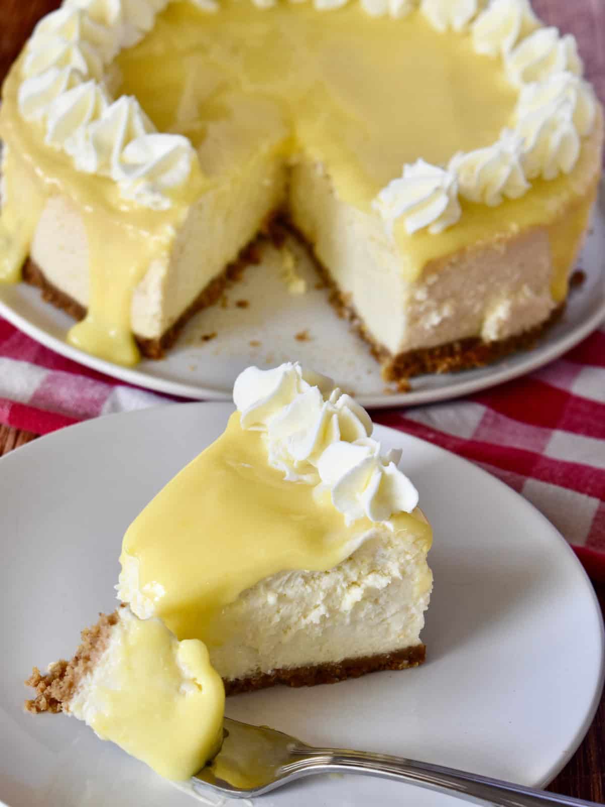 Lemon Ricotta Cheesecake slice on a white plate with a fork. 