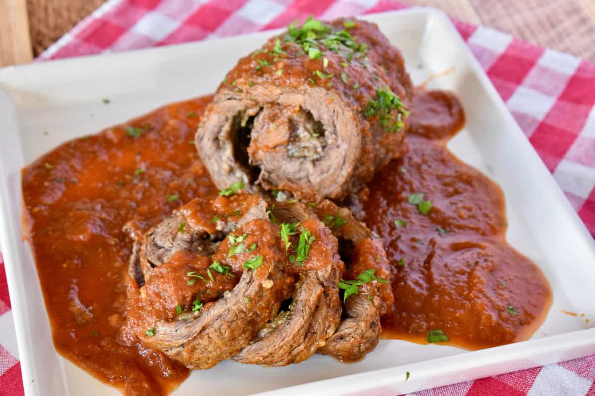 Authentic Italian Braciole on a white plate with marinara sauce on top. 