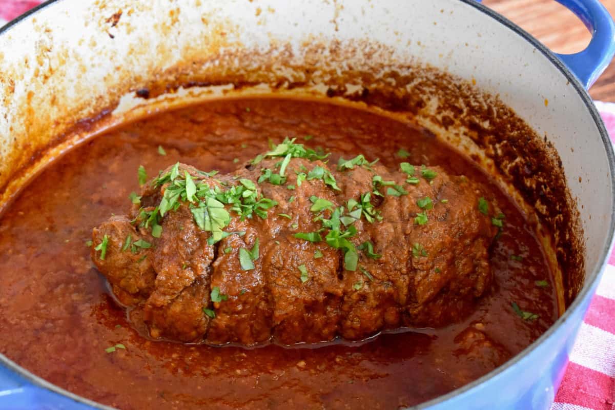 Cooked authentic Italian braciole in marinara sauce with parsley sprinkled on top. 