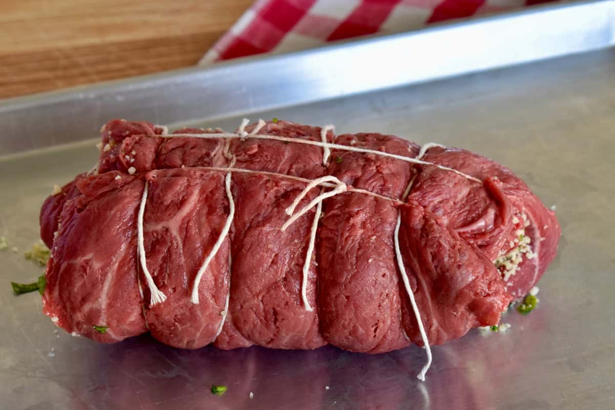 Flank steak rolled up jelly roll style and tied with kitchen twine. 