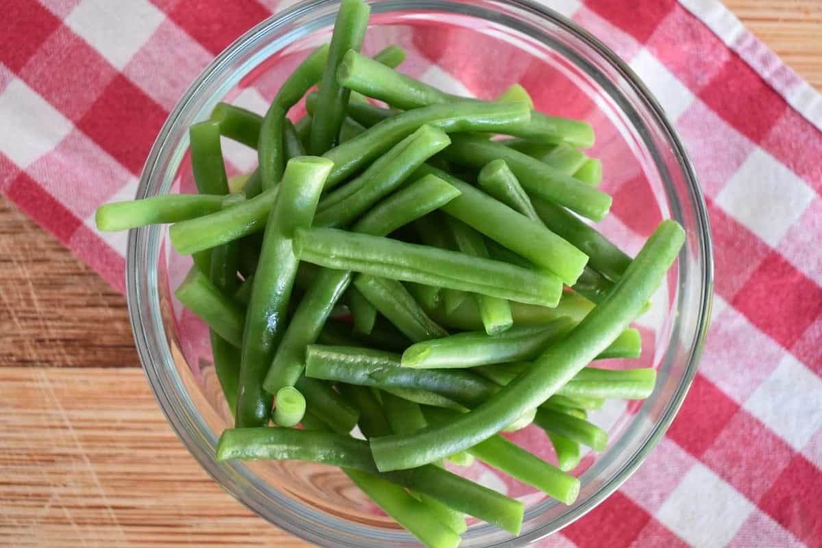 Cooked green beans in a glass bowl. 
