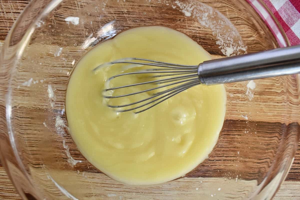 White chocolate and butter melted together in a glass bowl with a whisk.