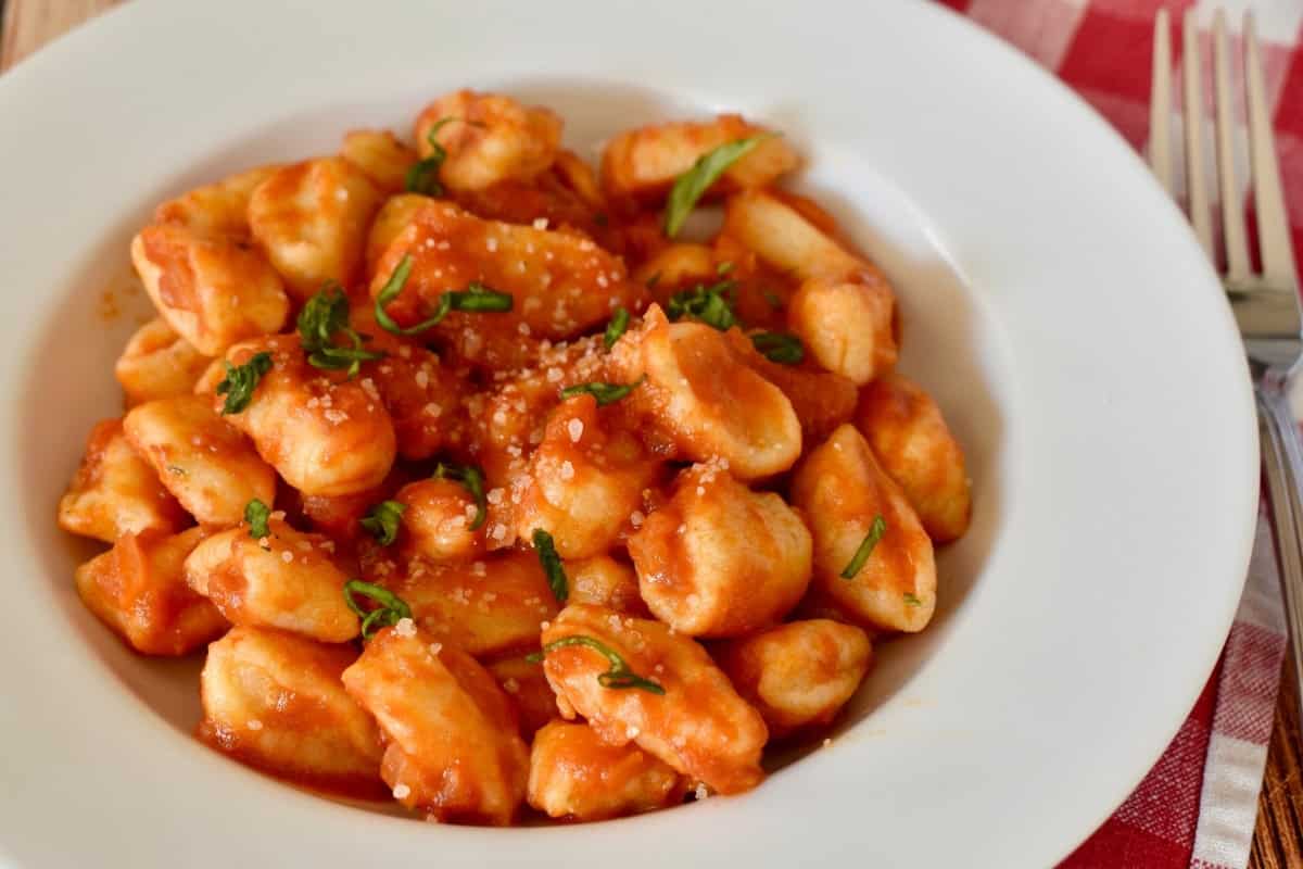 Ricotta gnocchi in butter tomato sauce in a white bowl. 