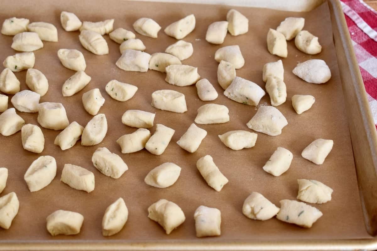 A tray of uncooked ricotta gnocchi on a table.