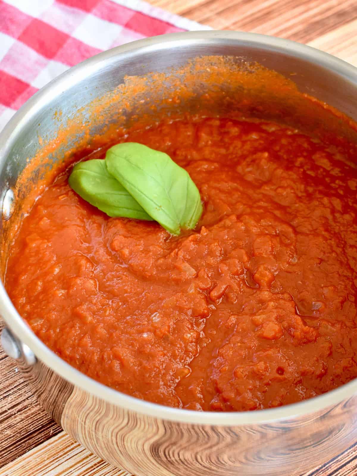 Tomato Butter Sauce in a saucepan with a basil leave on top.