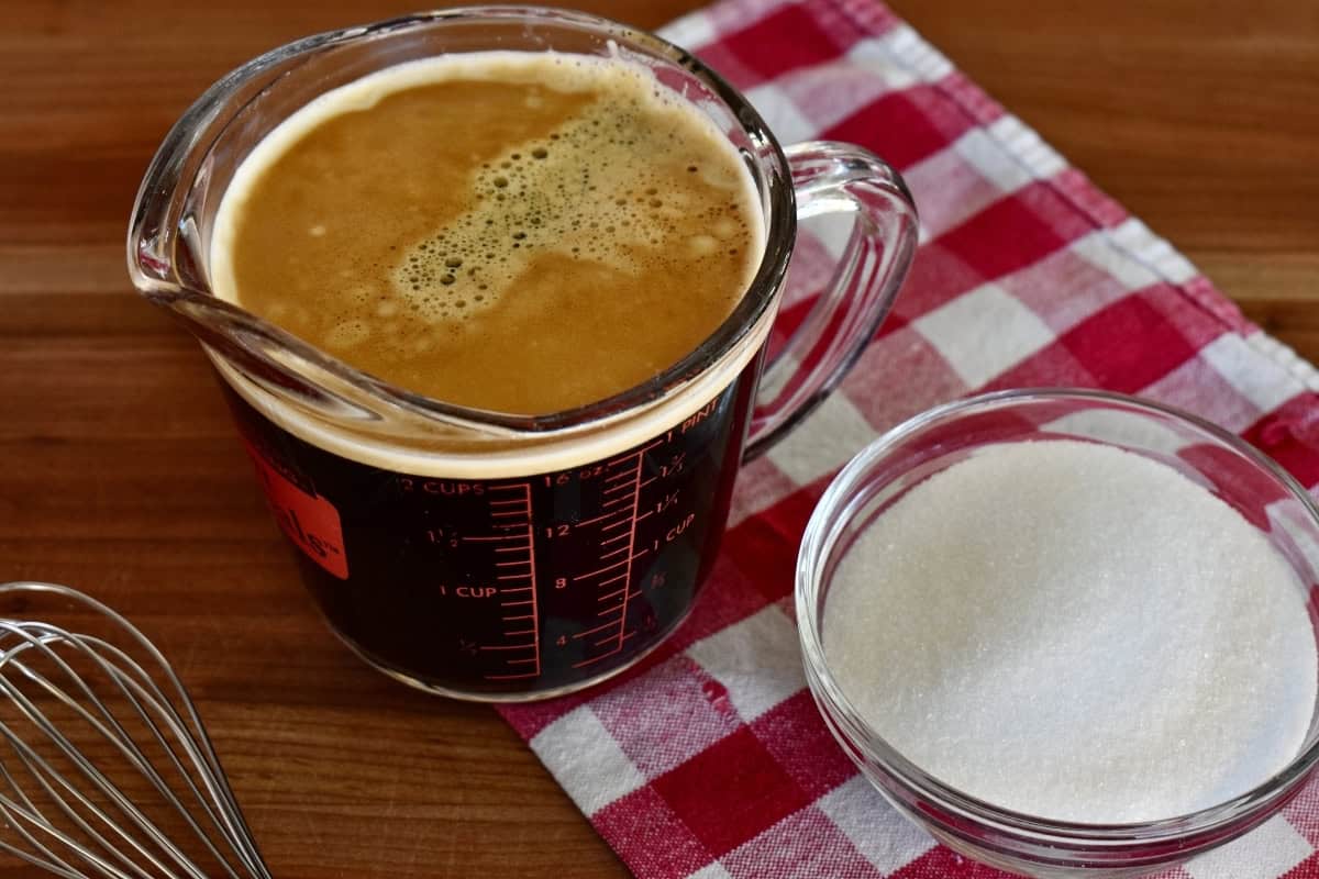 Strong coffee and sugar in measuring cups on a countertop. 