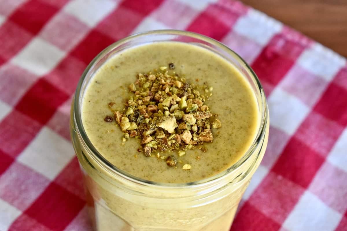 Italian pistachio cream in a glass jar with crushed pistachios on top. 