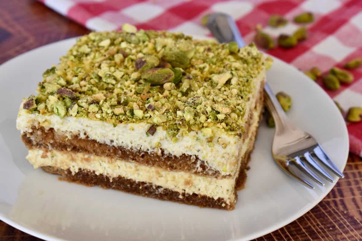 Slice of pistachio tiramisu on a white plate. 