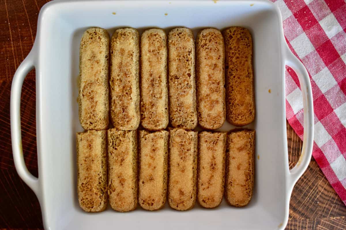 Soaked ladyfingers in the bottom of a white baking pan. 