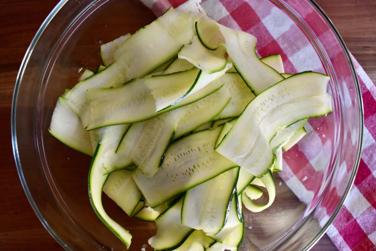 Thinly sliced zucchini in a glass bowl. 