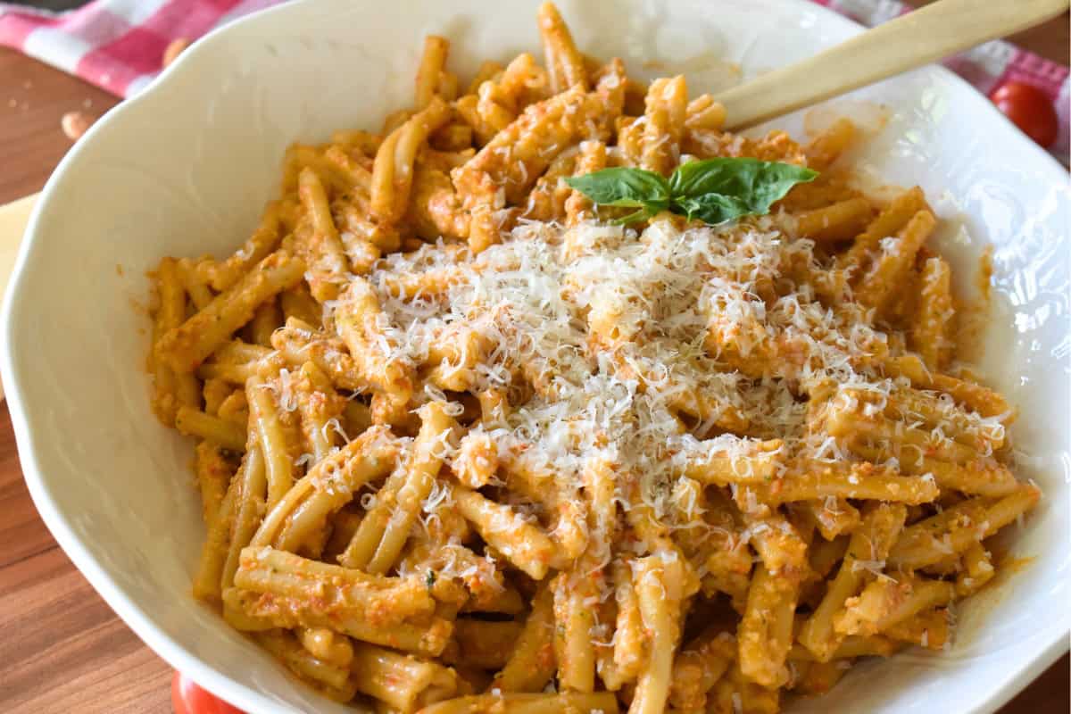 Sicilian pesto tossed with penne in a white bowl. 
