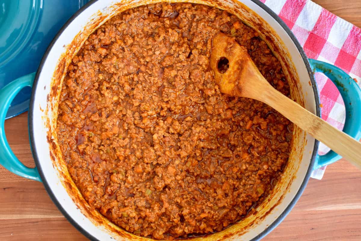 Bolognese Sauce in a large dutch oven with a wooden spoon. 