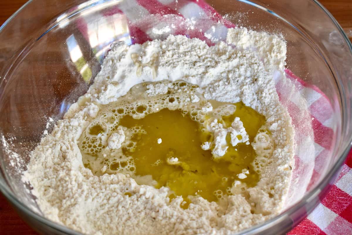 Flour, olive oil, and white wine in a glass bowl. 