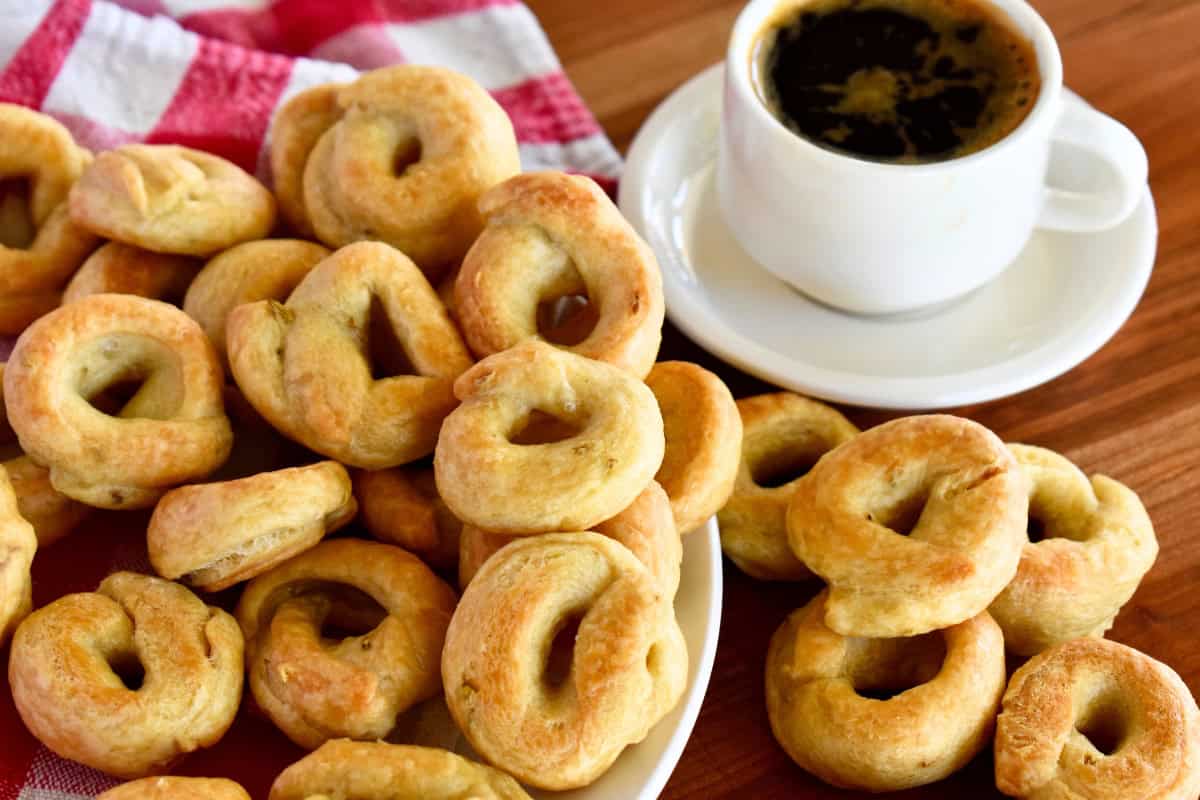 Taralli recipe on a white plate with a cup of coffee next to it. 